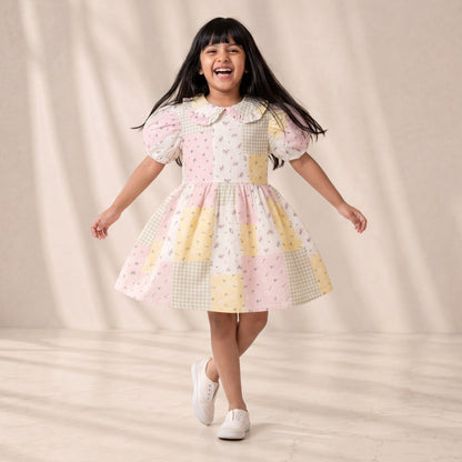 Young girl wearing a colorful dress with a patterned design on a neutral background