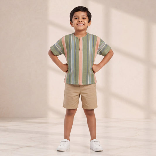 Child wearing a striped shirt and shorts standing against a plain background