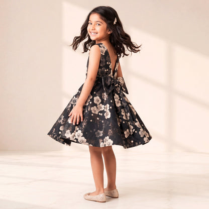 Young girl in a floral dress standing against a plain background