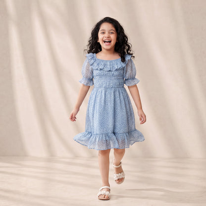 Young girl in a blue dress standing against a beige background