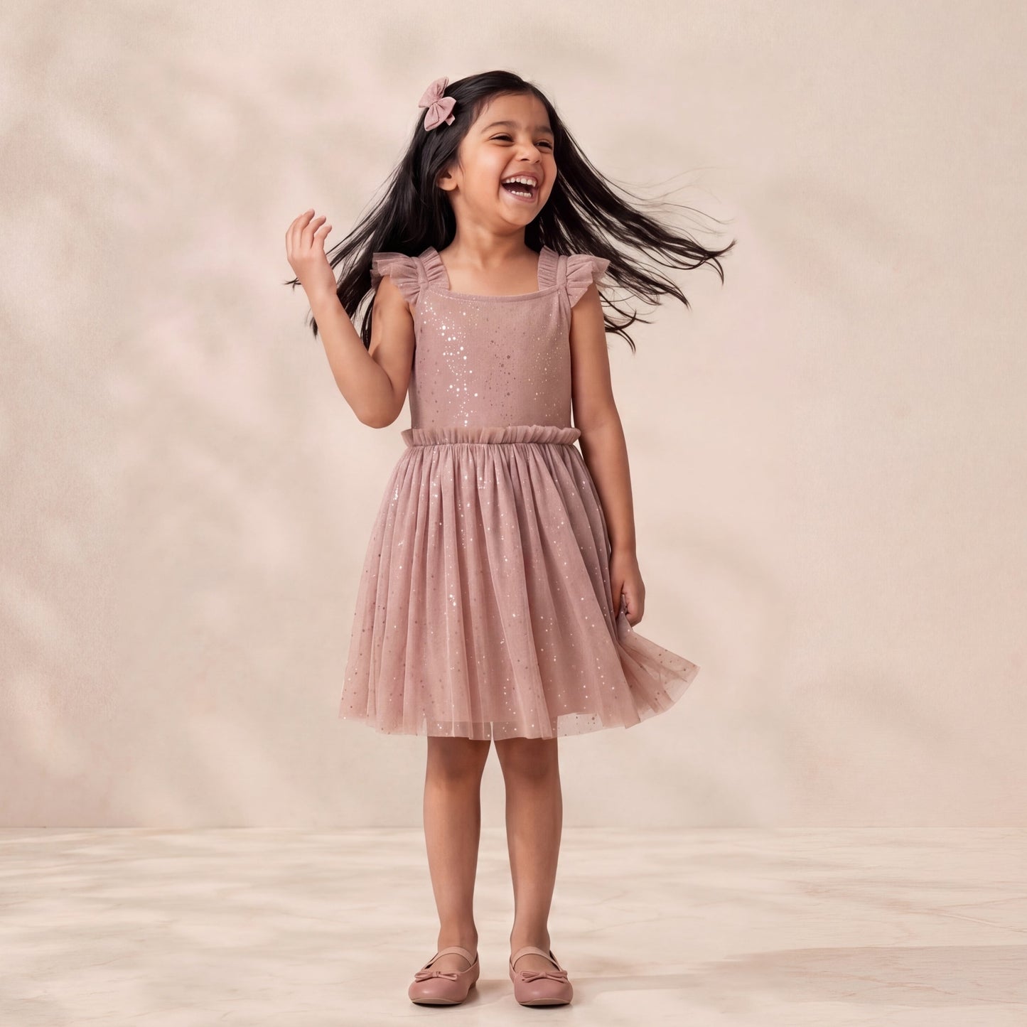 Young girl in a pink dress standing against a plain background