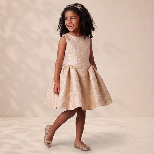 Young girl in a beige floral dress standing against a plain background