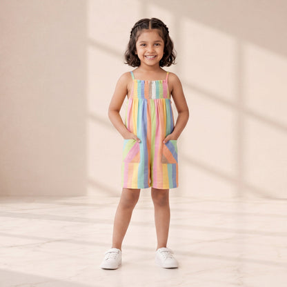 Young girl wearing a colorful dress standing in a softly lit room.
