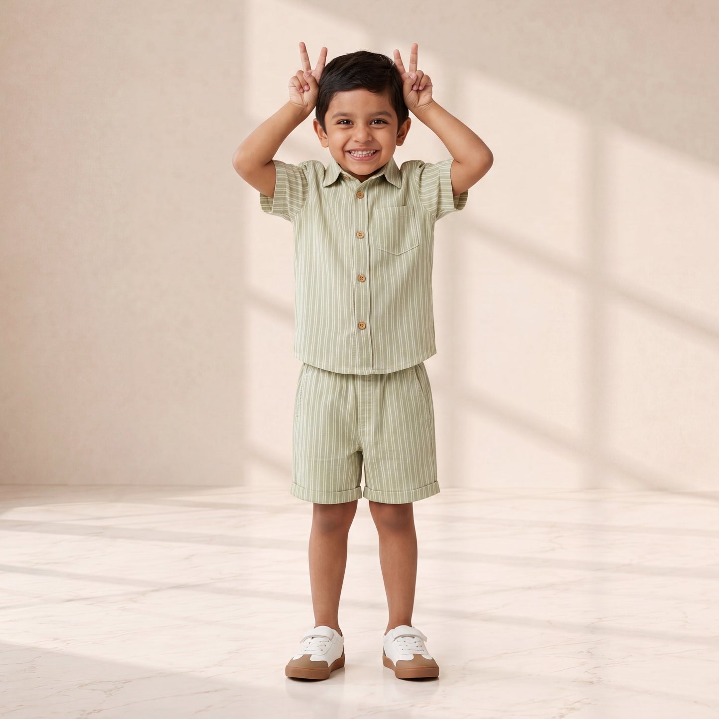 Child wearing a green striped outfit standing in a well-lit room with soft shadows.