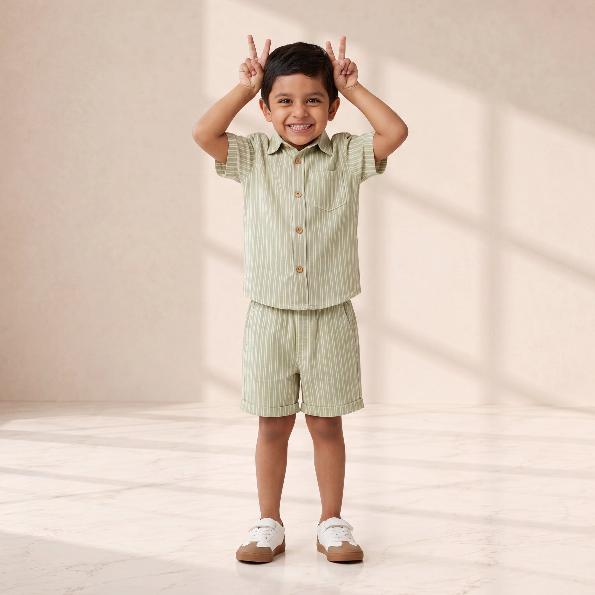 Child wearing a green striped outfit standing in a well-lit room with soft shadows.