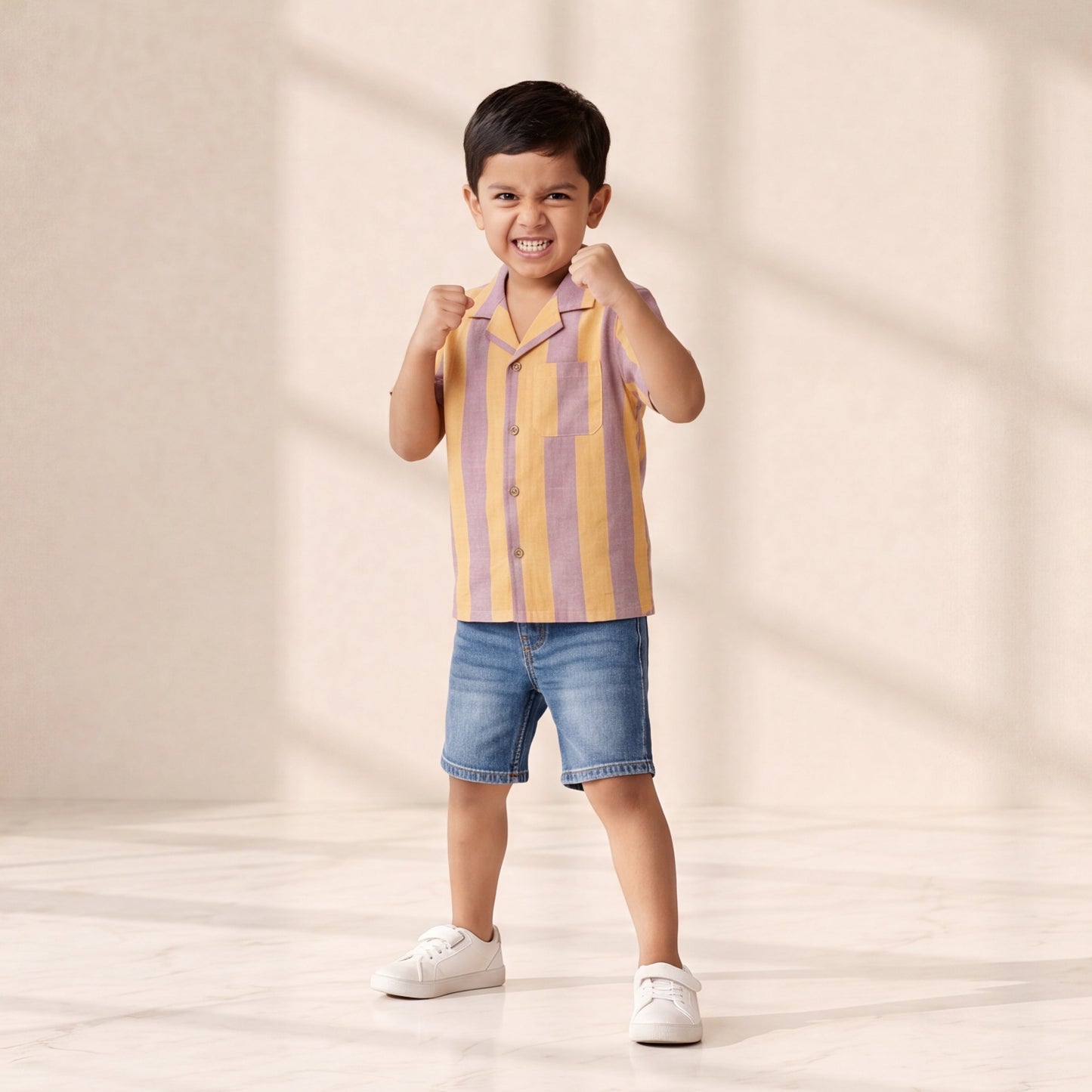 Child wearing a striped shirt and shorts on a plain background