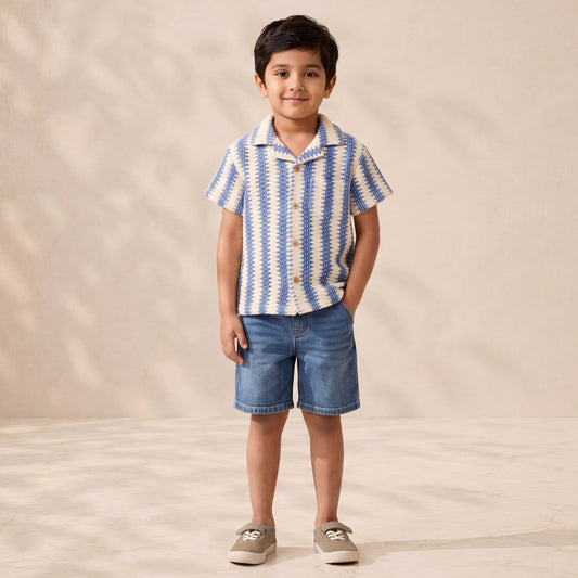 Child wearing a blue and white striped shirt and denim shorts on a beige background