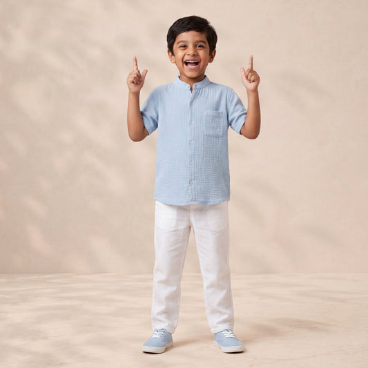 Child wearing a light blue checkered shirt and white pants on a beige background