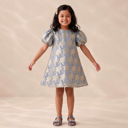 Young girl wearing a patterned dress against a plain background