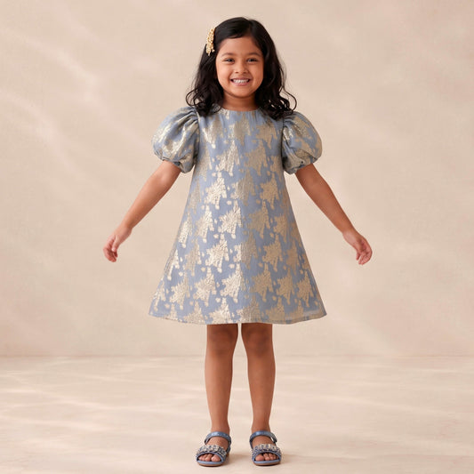 Young girl wearing a patterned dress against a plain background