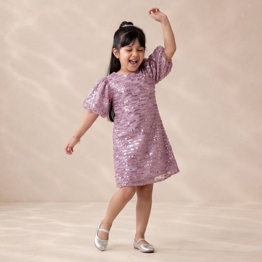 Young girl in a pink sequin dress posing against a beige background