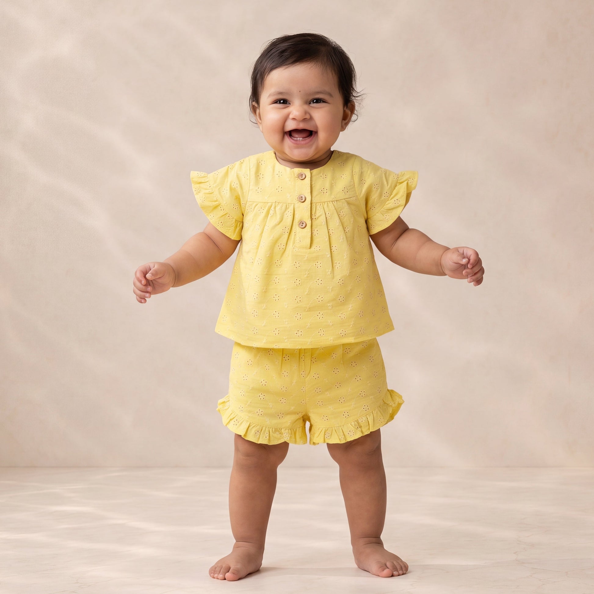 Baby in a yellow outfit standing on a beige background