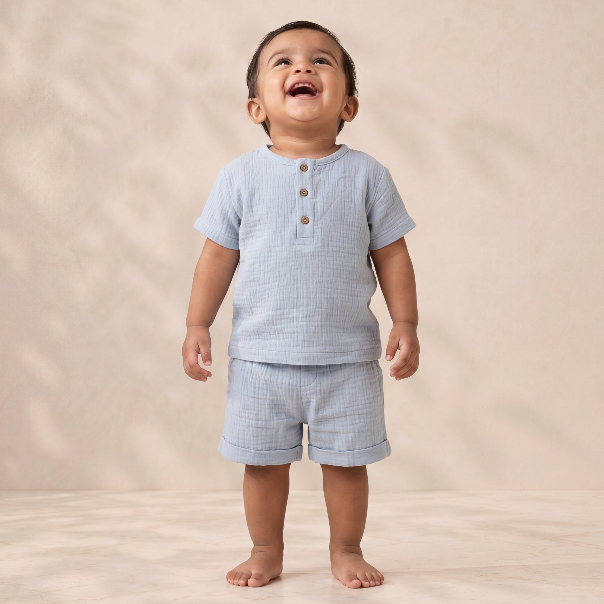Child wearing a light blue checkered outfit on a beige background