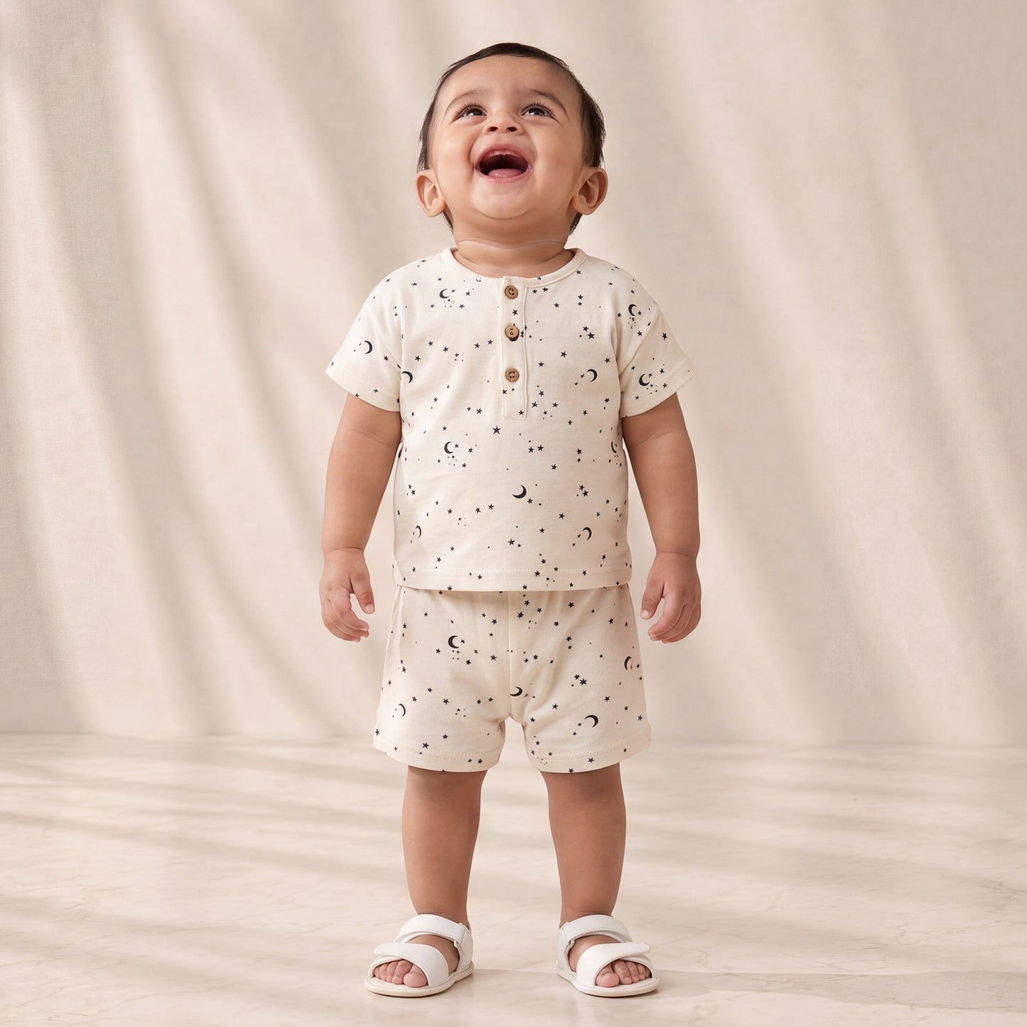 Child wearing a white outfit with small patterns on a plain background