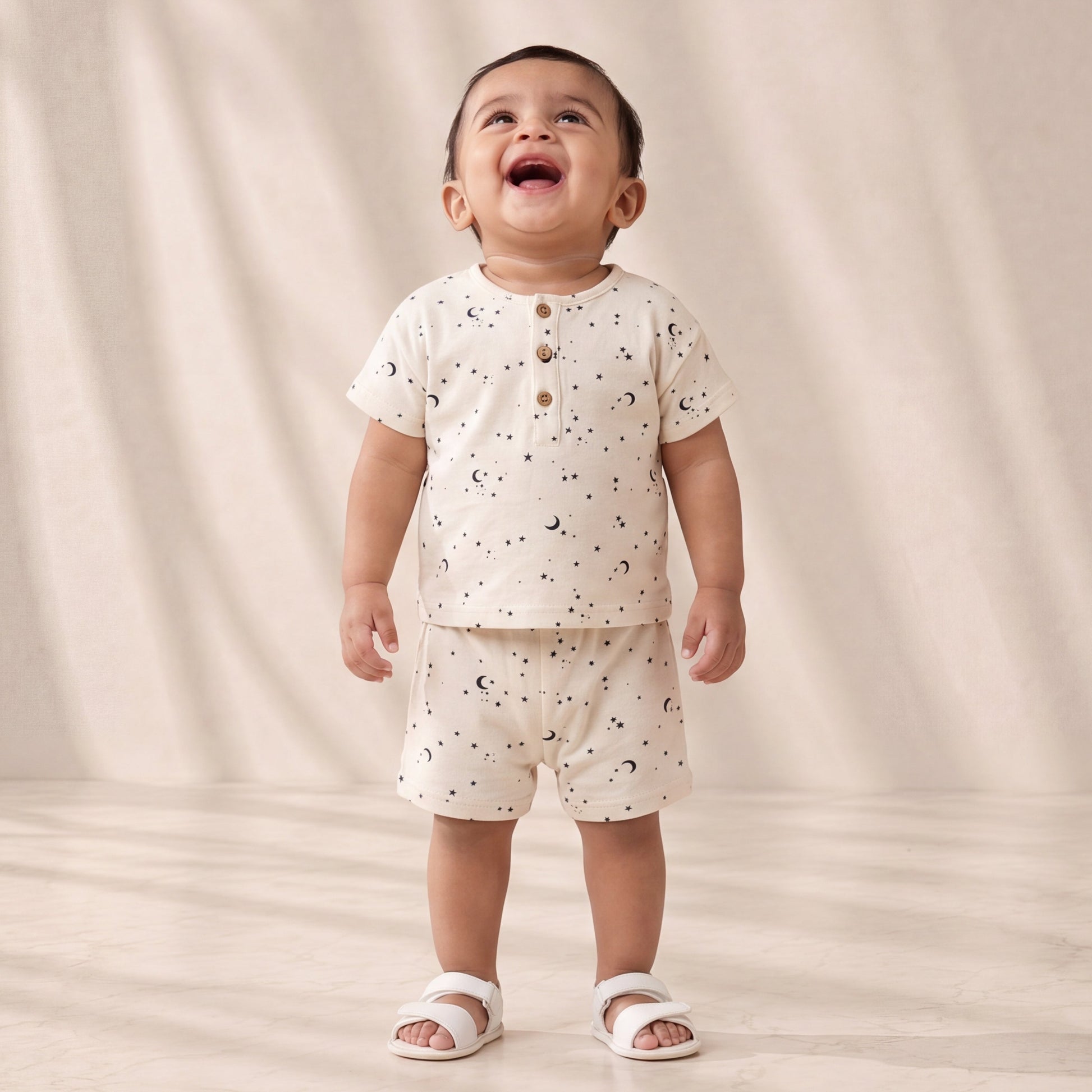 Child wearing a white outfit with small patterns on a plain background