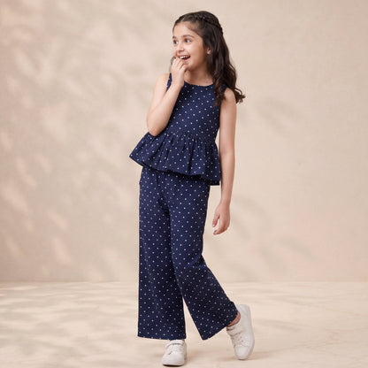 Young girl wearing a navy polka dot outfit on a beige background