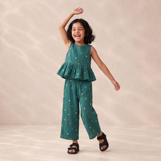 Child wearing a green outfit with colorful patterns on a beige background