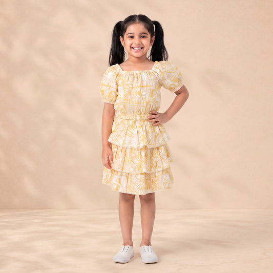 Young girl wearing a yellow and white patterned dress on a beige background