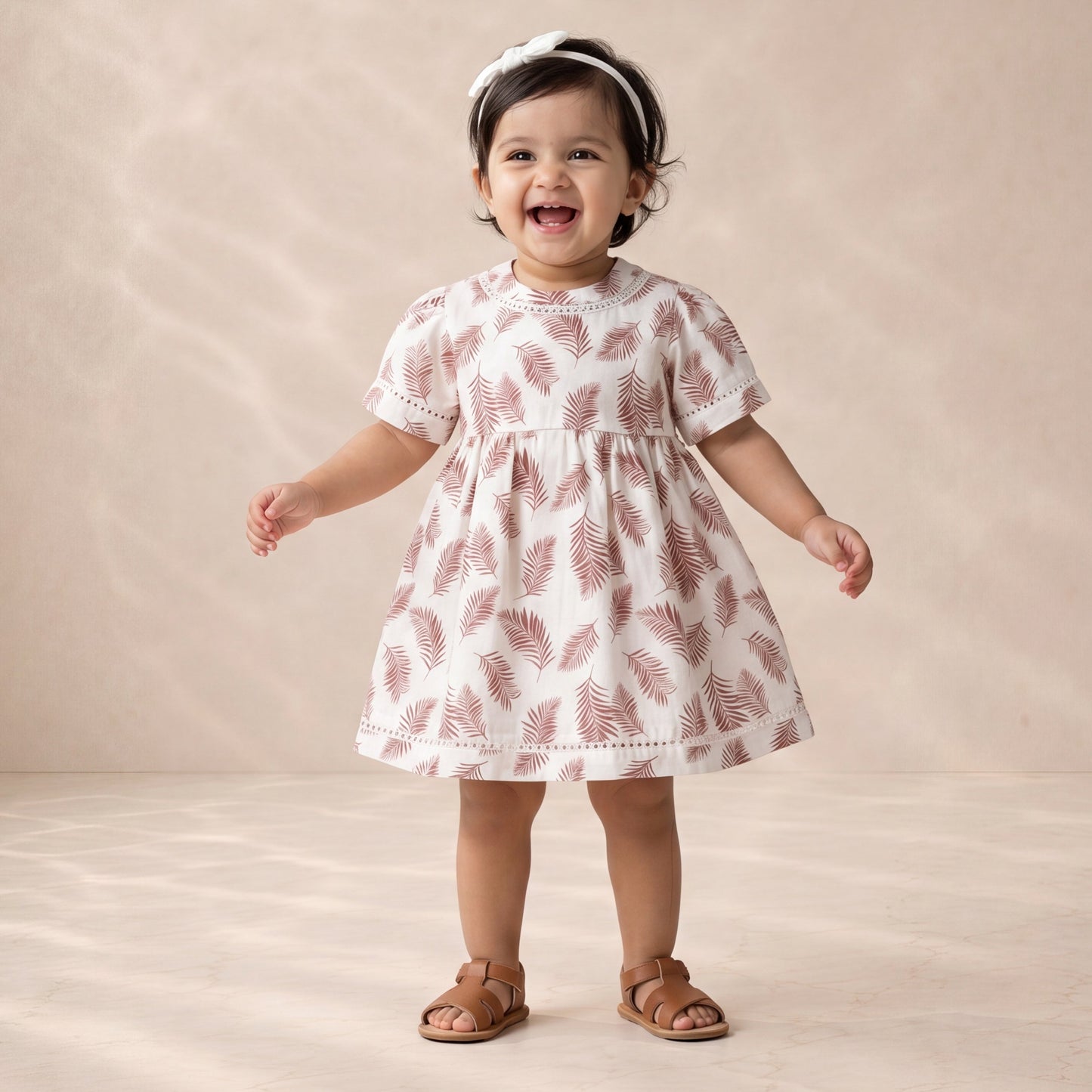 Child wearing a white dress with red patterns on a beige background