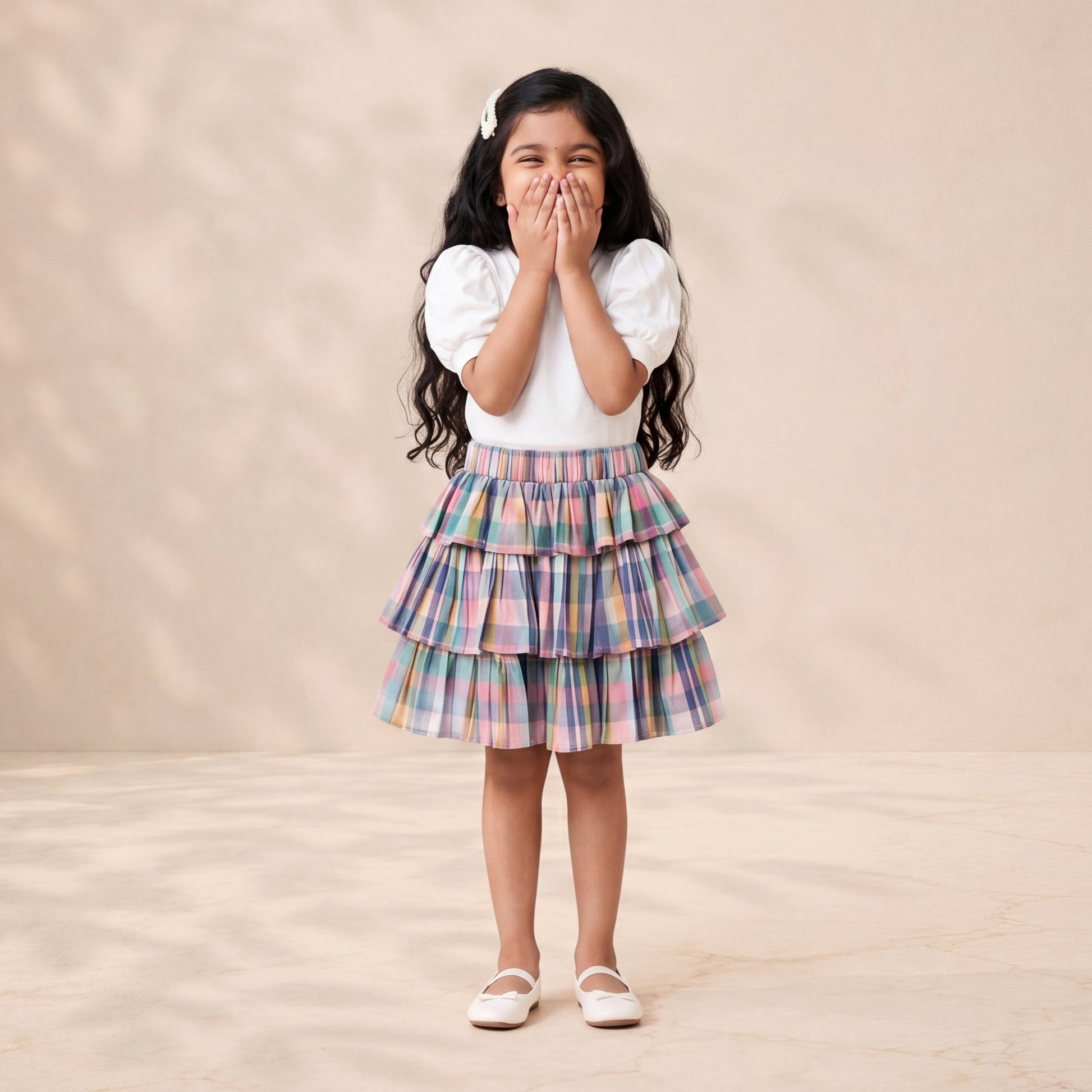 Young girl in a plaid skirt and white top standing against a beige background